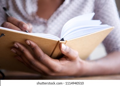 close up portrait of female hands holding pen and book - Powered by Shutterstock