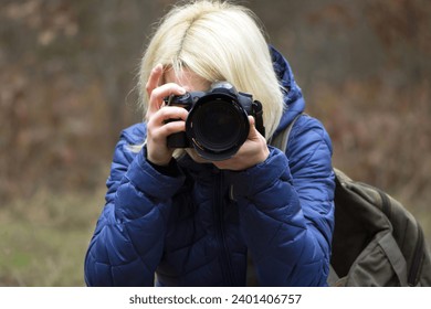 close up portrait of female photographer taking photos with digital camera. girl photographer with a camera in autumn in nature. Travel and photography. Young woman photographer, blogger