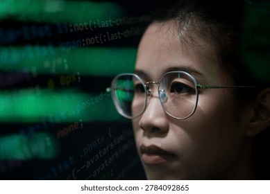 Close up portrait of a female software developer focusing on cybersecurity data displayed on digital screens in a dark office environment. The image represents concentration, artificial intelligence technology, software engineering, and digital security operations.