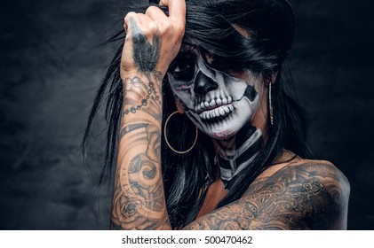 Close up portrait of female with sugar skull make up and tattooed arm.