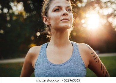 Close Up Portrait Of Fit Young Woman In Sportswear Standing Outdoors And Looking Away. Confident Fitness Model In Park.