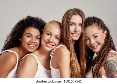Close up portrait of four cheerful young diverse women, female friends smiling at camera while posing together isolated over grey background. Diversity, beauty, friendship concept. Horizontal shot - Shutterstock ID 1881507541