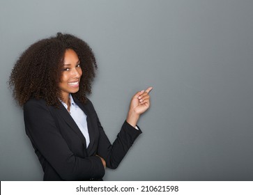 Close up portrait of a friendly business woman pointing finger on gray background