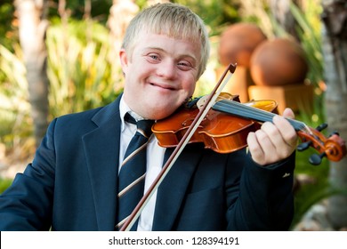 Close up portrait of friendly handicapped boy playing violin outdoors.
