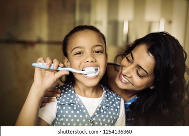 Close up portrait of girl brushing teeth with mother in bathroom - Powered by Shutterstock