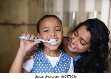 Close up portrait of girl brushing teeth with mother in bathroom - Powered by Shutterstock