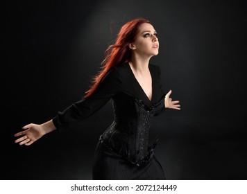 close up portrait of  girl wearing a fantasy witch black costume.    pose  gestural movements as if casting a spell, isolated on studio background.
