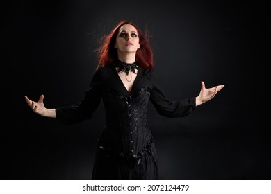 close up portrait of  girl wearing a fantasy witch black costume.    pose  gestural movements as if casting a spell, isolated on studio background.