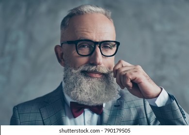 Close up portrait of grinning old-fashioned trendy elegant wealthy professional flirty trendsetter hipster grandpa sharp dressed with maroon bow-tie twisting white mustache isolated on grey background
