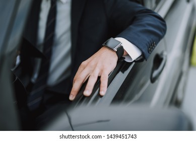 Close up portrait of guy wearing black costume and wristwatch while sitting by open car window - Shutterstock ID 1439451743