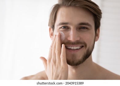Close up portrait handsome 30s man applying facial cream smile look at camera, after shave beauty skincare products for smooth healthy moisturizing hydrated skin, skin-care cosmetics for men concept - Shutterstock ID 2043915389