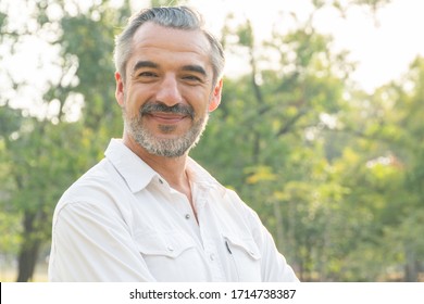 Close Up Portrait Of Handsome Caucasian Senior Men Smile In White Shirt. Happy Smart Confident Elderly Man Look At Camera. Business Casual Lifestyle At Park. Healthy Retirement Insurance Concept