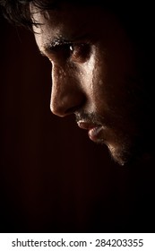 Close Up Portrait Of A Handsome Indian Young Angry Man Sweating Over Dark Background