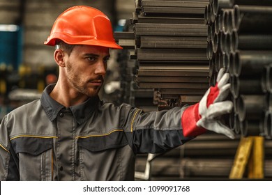 Close Up Portrait Of A Handsome Male Industrial Engineer Wearing Protective Helmet Checking Steel Supplies At The Storage Of Manufacturing Company Copy Space. Job, Heavy Industry, Occupation