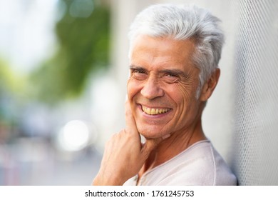 Close Up Portrait Handsome Older Man Smiling With Hand To Chin Outside