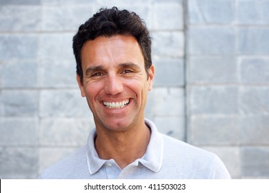 Close Up Portrait Of A Handsome Older Man Smiling Against Gray Background