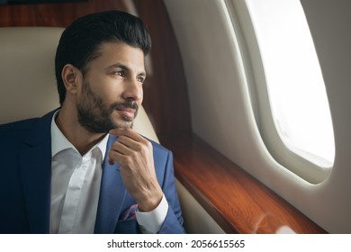 Close up portrait of handsome pensive arab businessman planning project sitting on airplane looking at window. Rich confident entrepreneur flying luxury private jet, successful business concept
