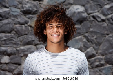Close up portrait of handsome young black man with curly hair smiling outside