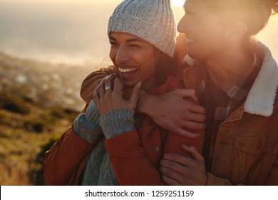 Close up portrait of handsome young man hugging his woman and smiling. Beautiful couple outdoors together on a winter day. - Shutterstock ID 1259251159