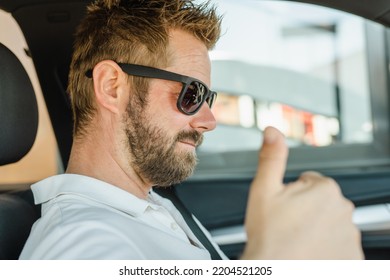 Close Up Portrait Of Handsome Young Man Wearing Sunglasses In The Car Showing Thumb Up.