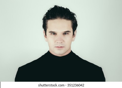 Close Up Portrait Of A Handsome Young Man Looking At Camera. Goodlooking Male Face In Black Dress On White Background Not Isolated.