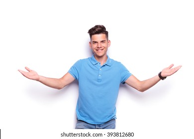close up portrait of handsome young man in jeans and blue polo shirt welcoming with open arms while looking at the camera in white isolated studio background