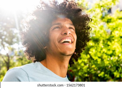 Close up portrait handsome young North African man with afro hair laughing outside 