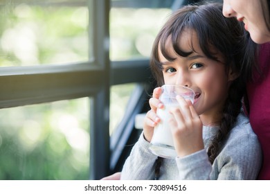 Close up portrait of happy Adorable girl holding glass with milk. 