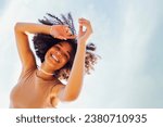 Close up portrait of happy african american female teenage smiling sweetly at the camera. black girl with afro curls hairstyle. Laughing teen against the sky. Free space for text