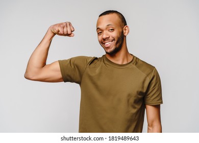 Close up portrait of a happy african american man wearing t-shirt flexing bicep arm muscle - Powered by Shutterstock