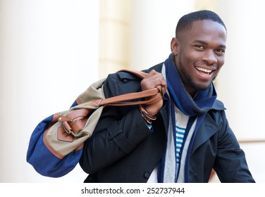 Close up portrait of a happy african american man standing outdoors with bag