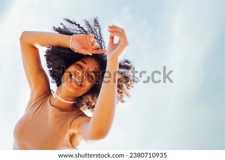 Close up portrait of happy african american female teenage smiling sweetly at the camera. black girl with afro curls hairstyle. Laughing teen against the sky. Free space for text