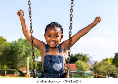 Close up portrait of Happy African kid raising arms on swing in park. - Powered by Shutterstock