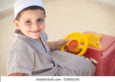 Close up portrait of a happy Arabic boy driving a toy car