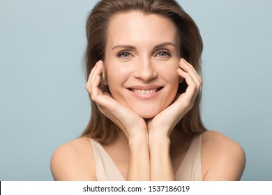 Close Up Portrait Of Happy Beautiful Caucasian Woman Isolated On Blue Studio Background Look At Camera Demonstrate Clean Healthy Skin, Smiling Millennial Female Show Result After Cream Serum Treatment