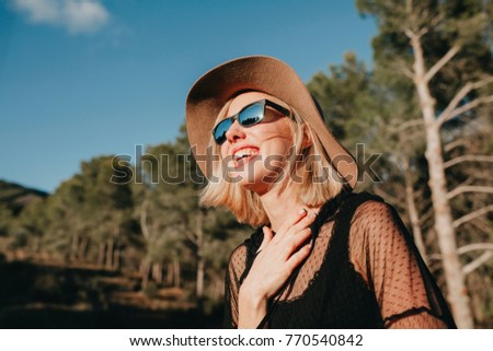 Similar – Kühle blonde Frau mit Sonnenbrille und schwarzem Kleid, die sich bei Sonnenuntergang in der Natur amüsiert.