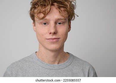 Close up portrait of happy calm young handsome freckled red haired ginger man with blue eyes wearing gray t-shirt casual wear smiling showing emotions and posing for photo isolated on gray background. - Shutterstock ID 2255085557