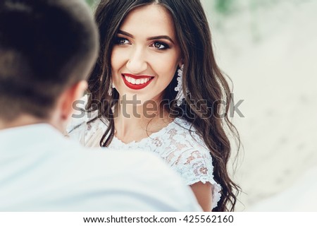 Close up portrait of happy couple. Beautiful young woman with long dark wavy hair with man outdoors. Cute newlyweds on their wedding ceremony.