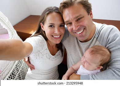 Close Up Portrait Of A Happy Couple Photographing Themselves With New Baby