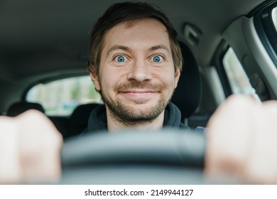 Close up portrait of happy excited driver begginer behind the wheel of his first car.