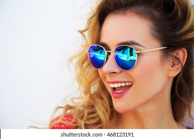 Close Up Portrait of Happy Fashion Woman in Sunglasses. Smiling Trendy Girl in Summer. White Wall Background Copy Space. Not Isolated Toned Photo.
