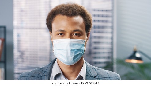 Close up portrait of happy handsome young African American male employee in medical mask looking at camera in room and smiling. Businessman at office in quarantine. Business, work, covid-19 pandemic - Powered by Shutterstock