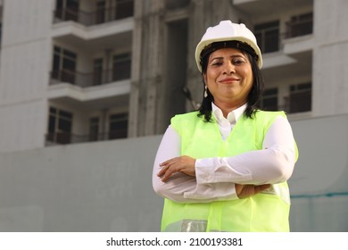 Close Up Portrait Of A Happy Indian Woman Construction Manager Wearing Helmet. Dedicated And Confident Female Engineer In Suit Is A Professional, Busy At Work On A Construction Site.