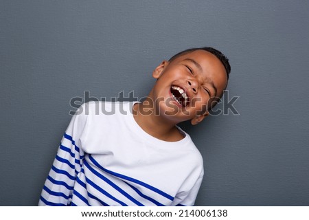 Close up portrait of a happy little boy smiling on gray background 