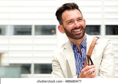 Close up portrait of happy mature man with beard looking away and smiling outdoors - Shutterstock ID 488680477