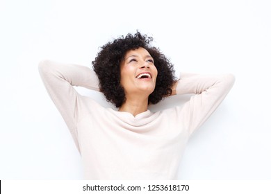 Close up portrait of happy older woman laughing with hands behind head against white backgorund
