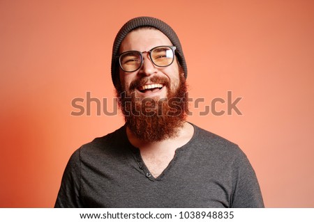 Close up portrait of happy smiling bearded hipster man with eyeglasses and looking confident at the camera