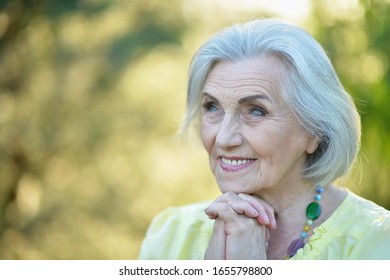Close up portrait of happy smiling senior beautiful woman in spring park