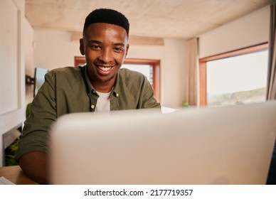 Close Up Portrait Of A Happy Young Adult Black African-American Male Smiling While Using His Laptop. Remote Working From His Modern Apartment