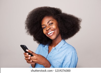 Close Up Portrait Of Happy Young African American Woman Smiling With Mobile Phone Against Isolated Gray Background